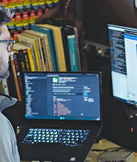 A man looking at a computer screen with code on it, alluding the development of types of AI.