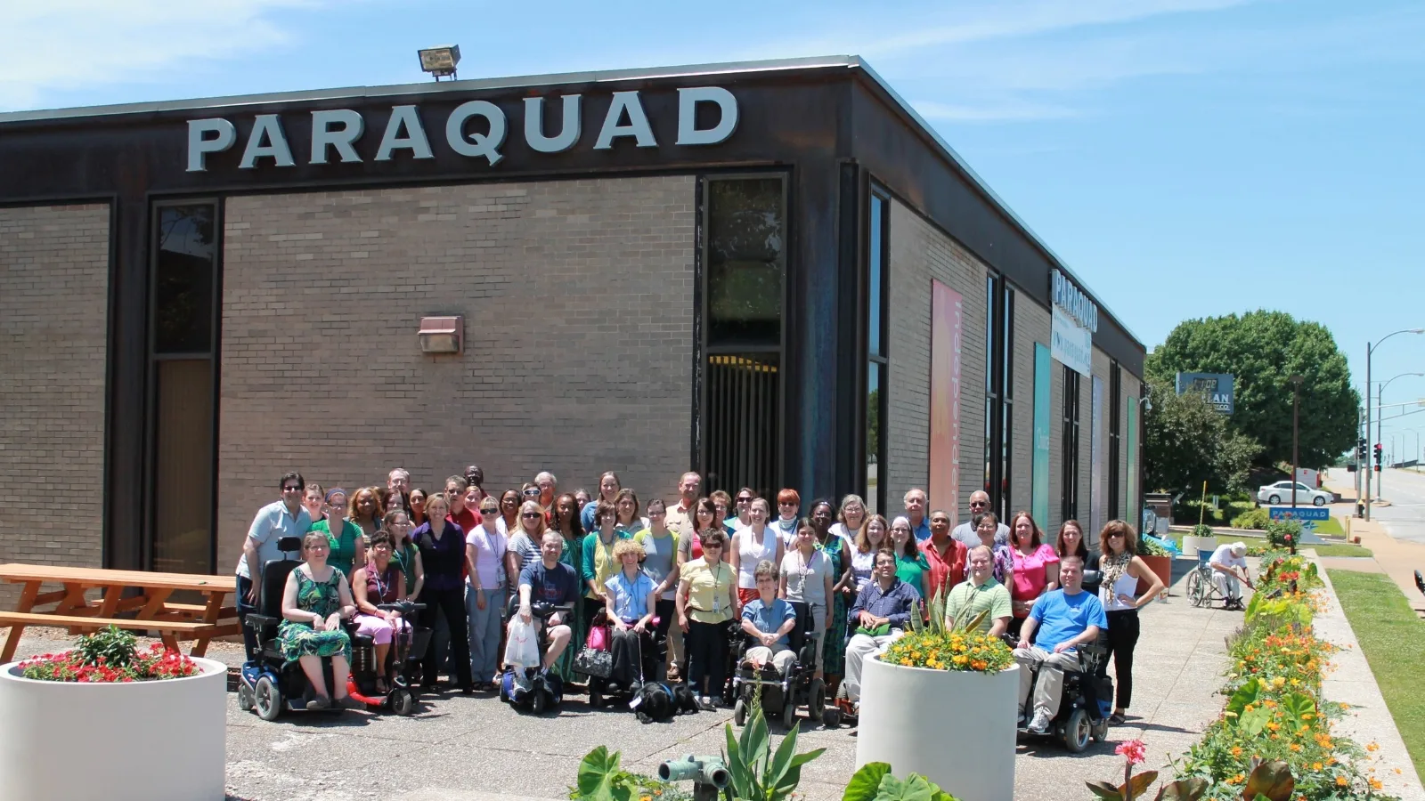 group of people posing in front of the Paraquad building