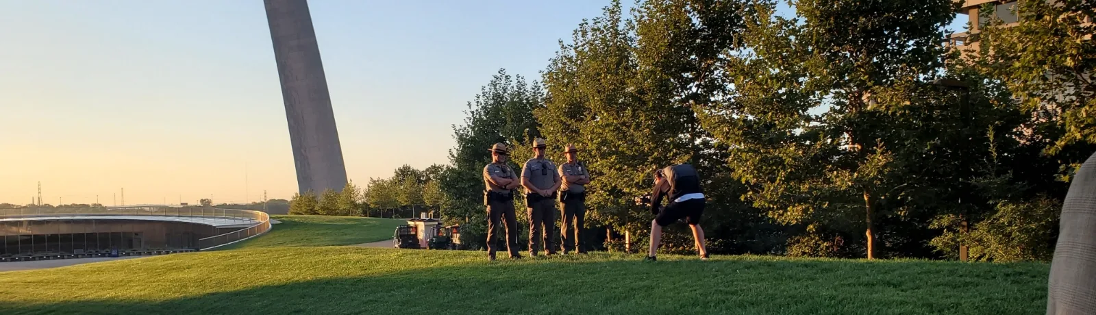 wide shot of videographer shooting 3 rangers in front of the arch