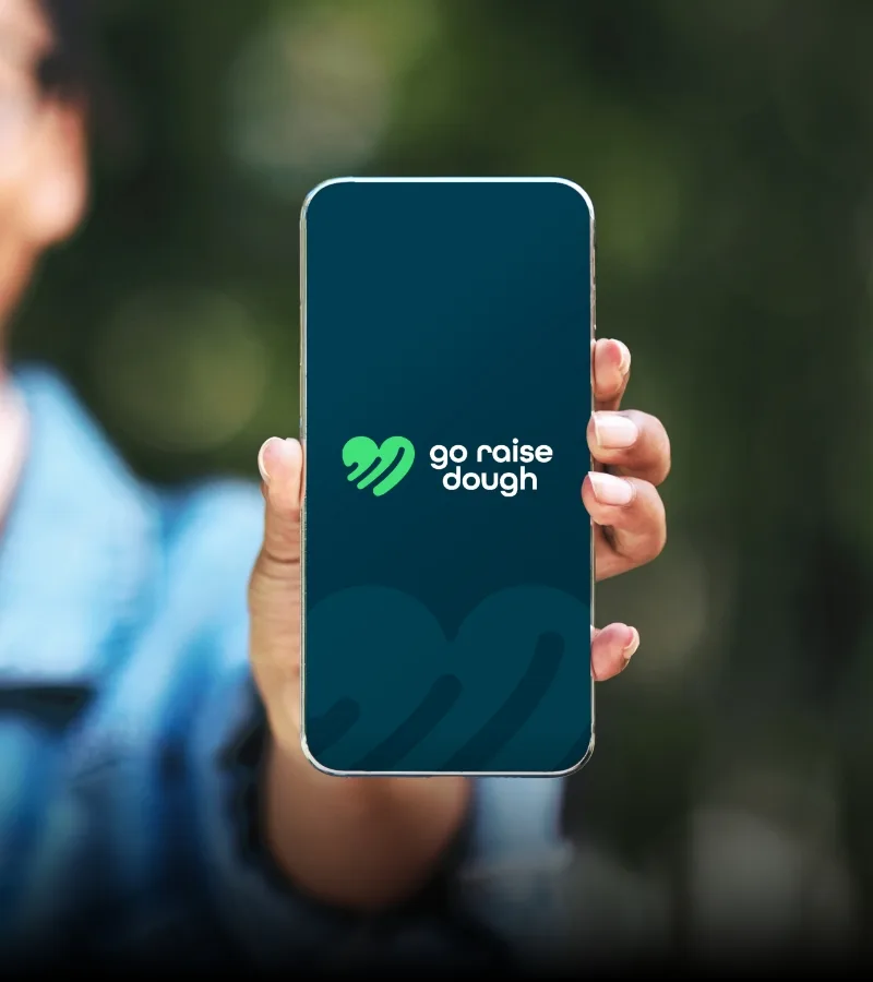 Young person holding phone with a go raise dough website splash screen.