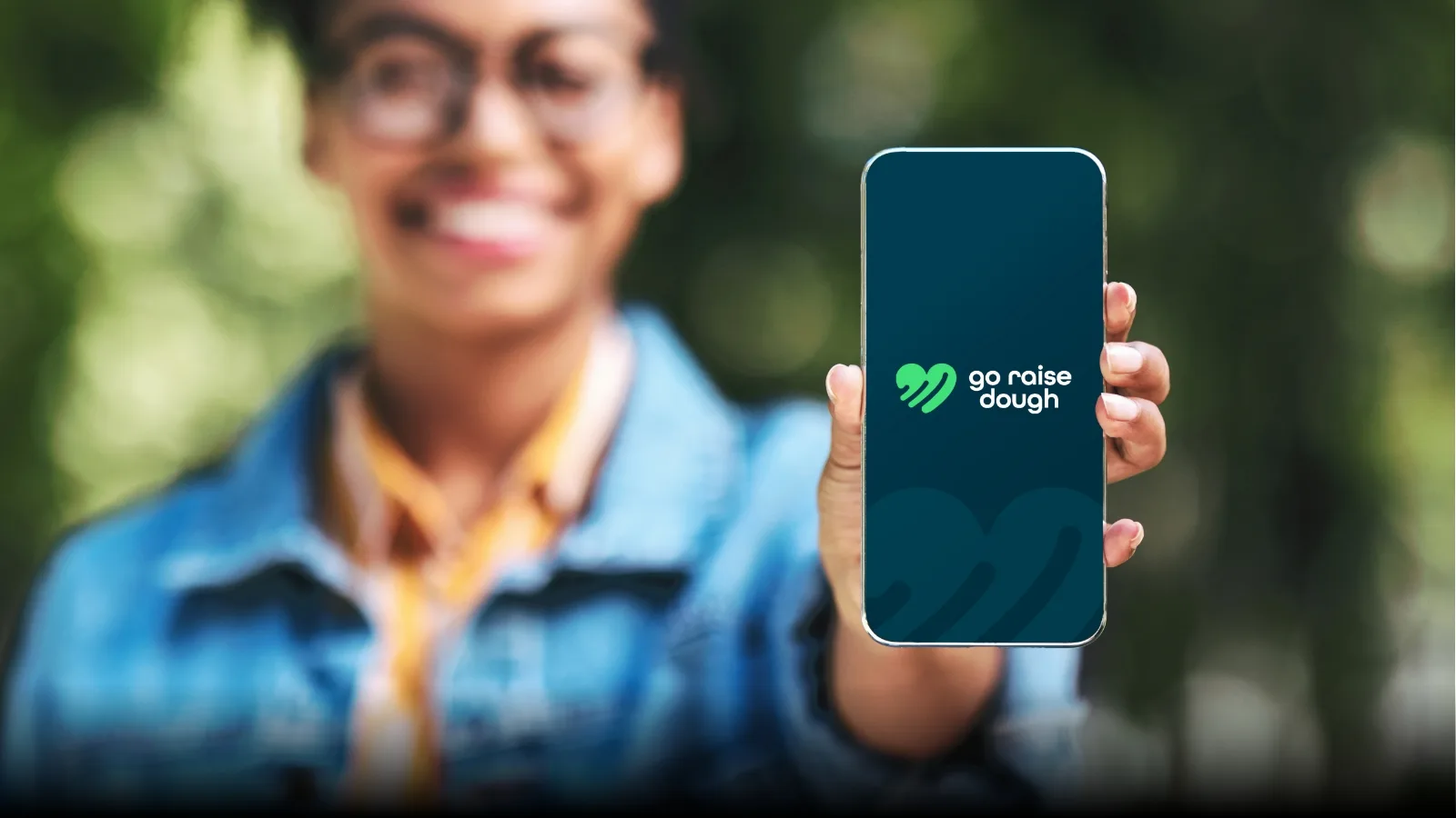 Young person holding phone with a go raise dough website splash screen.
