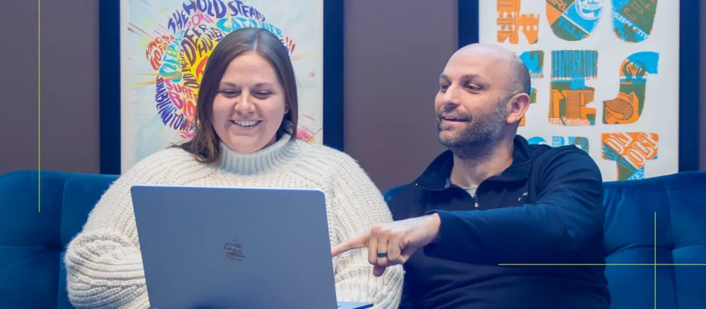 An account manager and a web developer sit on a couch brainstorming. 