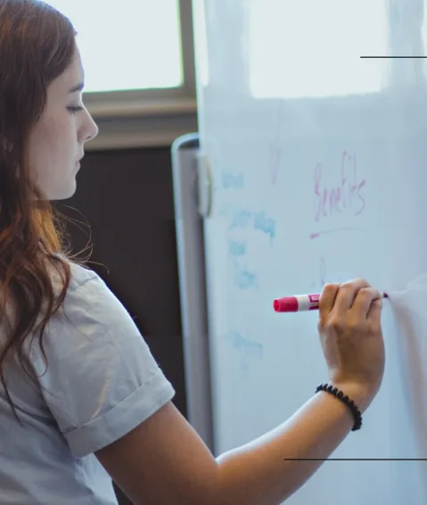 A staff member of Paradigm, a copywriting agency, writes on a whiteboard.