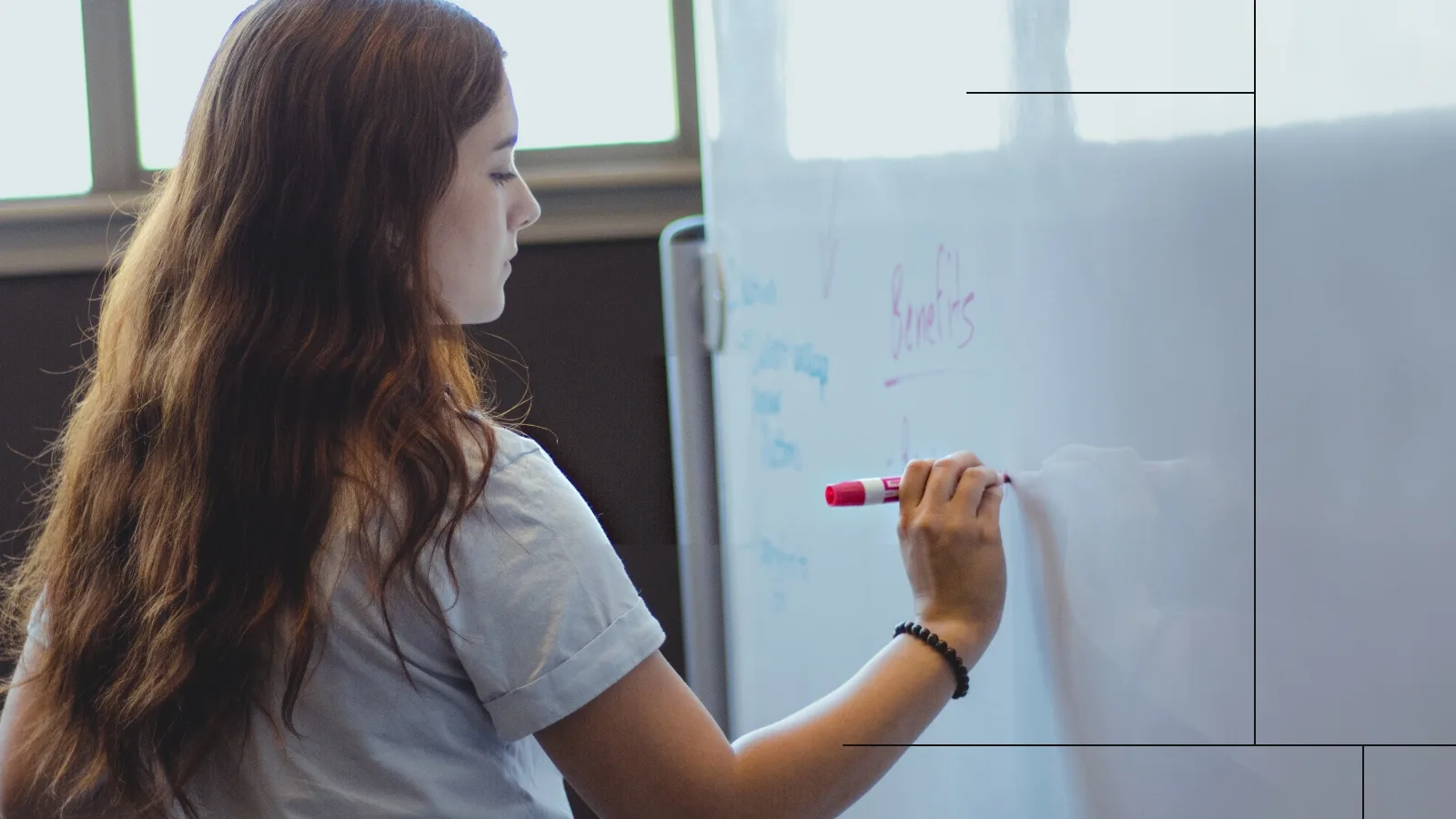 A staff member of Paradigm, a copywriting agency, writes on a whiteboard.
