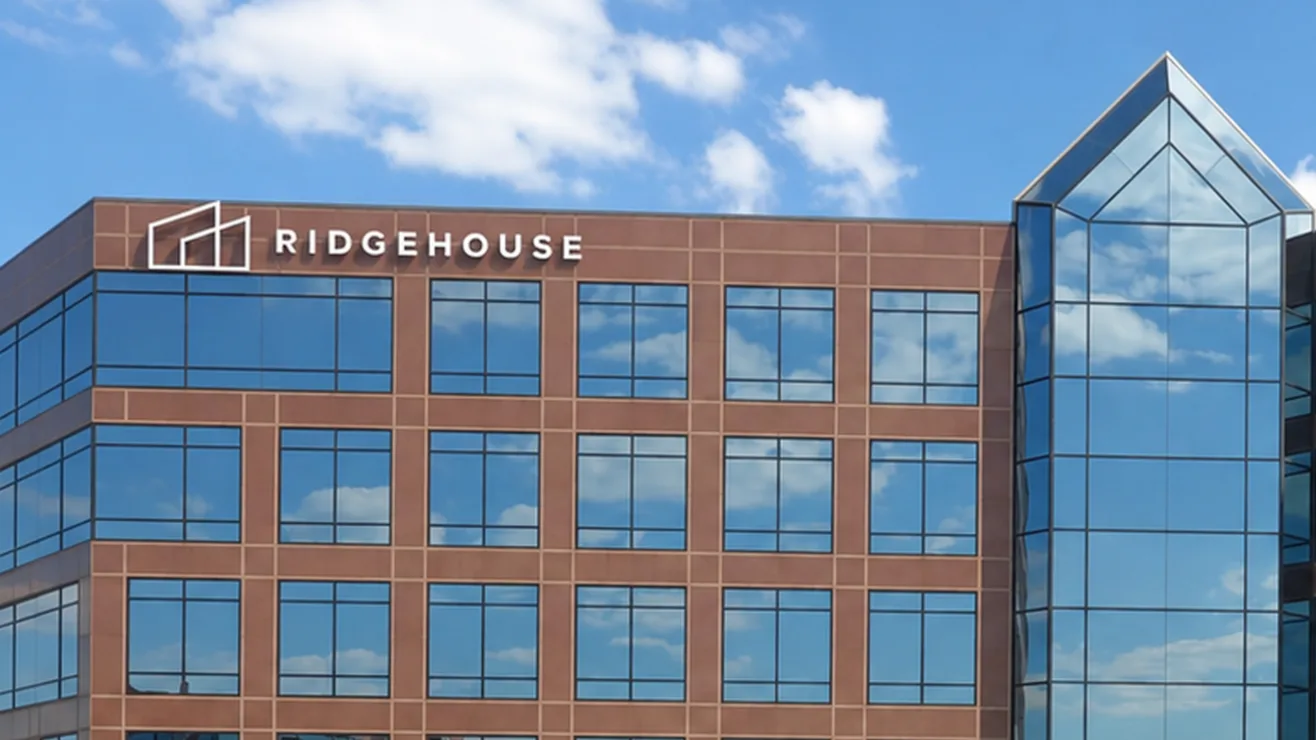 Exterior view of a modern brown and glass commercial building featuring a prominent white Ridgehouse logo on the upper facade.